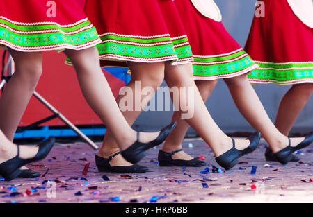 Russische Mädchen in traditionellen Kostümen tanzen auf der Bühne vor. Beine-Nahaufnahme Stockfoto