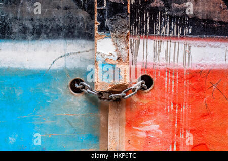 Kette mit Vorhängeschloss auf einer alten Holztür, zwei Farben, blau und rot lackiert Stockfoto