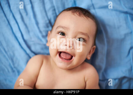 lächelnden Baby auf Bett blaue Decke hautnah Stockfoto