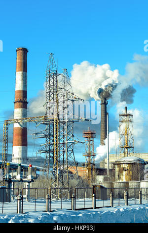 Industrielle Ansicht mit Luftschläuchen Verschmutzung. Winterlandschaft mit Hochspannung Getriebe Turm und Fabrik-Röhrchen. Ökologische Staub Konzept. Stockfoto