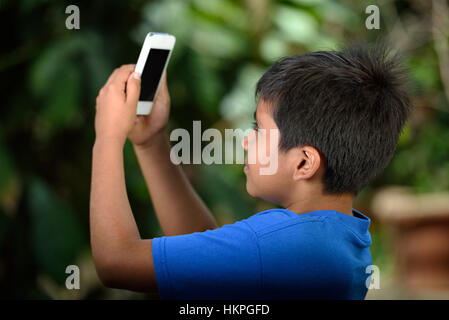 Junge mit Smartphone Aufnahme Fotos im park Stockfoto