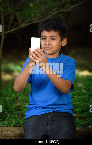 Kind mit Telefon im grünen Park aufgehoben Stockfoto