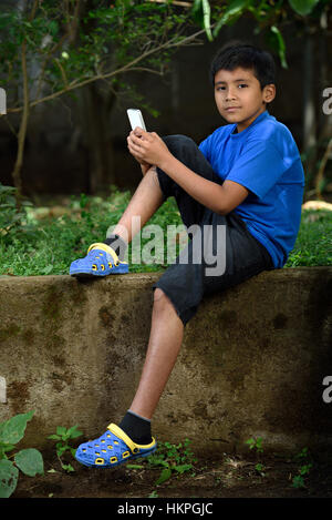 junge sitzen mit Smartphone in grünen park Stockfoto