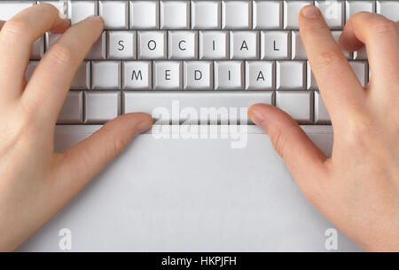 Hände auf einer silbernen Laptoptastatur tippen. Die Buchstaben auf den Tasten wurden gelöscht und neu geordnet, um nur "social Media" zu buchstabieren. Stockfoto