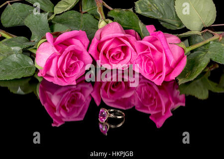 Drei Rosen, die rosa und einen Ring der gleichen Farbe sind Stockfoto