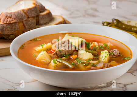 Gemüse Rindfleisch Suppe mit geschnittenem Brot und hot chili Peppers im Hintergrund Stockfoto