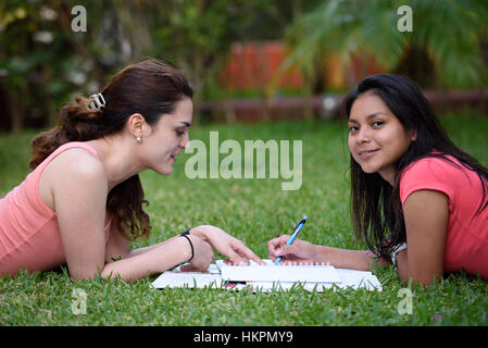 zwei Latino Mädchen studieren außerhalb im grünen park