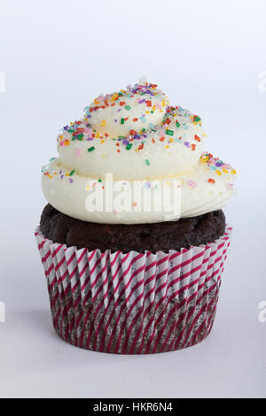 Einzelne Schokolade Cupcake mit Creme Zuckerguss und Regenbogen-Streusel Stockfoto