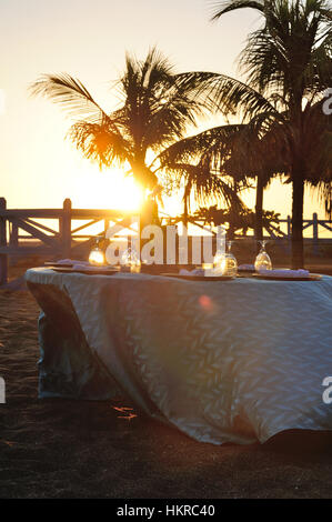 Tabelle für romantisches Abendessen am Strand im Abendlicht Stockfoto