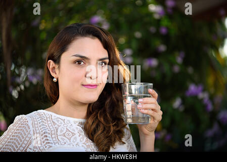 Mädchen mit Glas Wasser im grünen Park Hintergrund Stockfoto