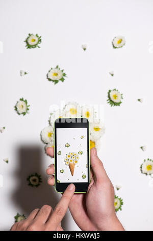 Hand nehmen Foto von Blumen in das Waffelhörnchen. Flach zu legen. Stockfoto