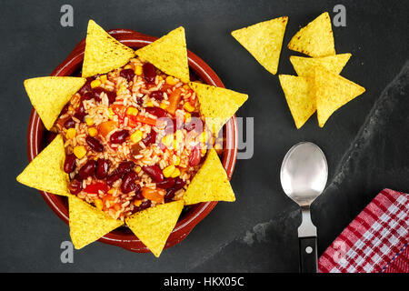 Vegetarisches Chili Con Carne in Schüssel mit Tortilla-Chips auf Schiefer Hintergrund, Ansicht von oben. Stockfoto