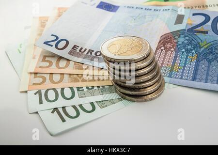 Geld-Euro-Münzen und Banknoten, die in verschiedenen Positionen auf einander gestapelt. Geld-Konzept. Detail der Euro-Währung auf dem Schreibtisch. Stockfoto