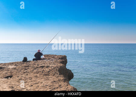 alten Menschen in den Rand des Ozeans auf Sedemenary Felsen Fischen Stockfoto