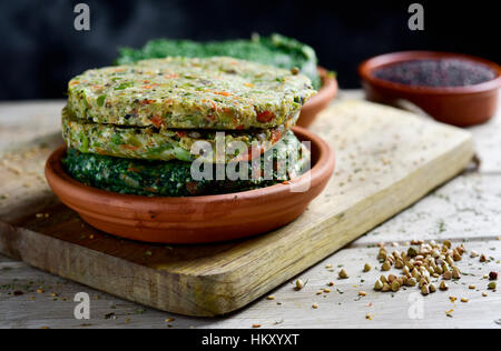 Nahaufnahme von einigen verschiedenen roh Veggie-Burger in eine Steingut-Platte auf einem rustikalen Holztisch Stockfoto