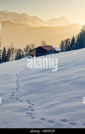 Fußspuren im Schnee in Richtung Holz-Ferienhaus in Bergen des Allgäu Stockfoto
