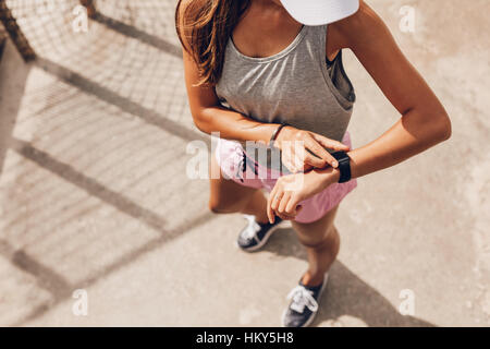 Ansicht von oben geschossen junge Frau Überprüfung Fitness Fortschritte auf ihrem smart-Uhr. Weibliche Läufer mit Fitness-app um Trainingsleistung zu überwachen. Stockfoto