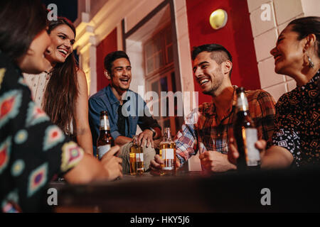 Gruppe von Freunden an einem Tisch auf dem Dach Party mit Bier. Junge Menschen auf Dach mit Getränken. Stockfoto