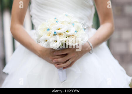 Weiße Rosen und Lisianthus Brautstrauß in der Hand der Braut Stockfoto