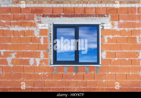 Standard außerhalb Hahn wird es am Rand eine neue Kunststoff-Fenster eingefügt. Die roten nicht verputzten Mauer des ländlichen Hauses. Himmel Spiegelung im Glas Stockfoto