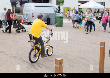 Mann mit dem gelben Klassiker Raleigh Chopper Fahrrad in einer Fußgängerzone Stockfoto