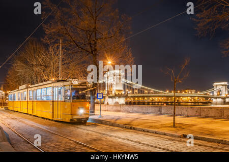 BUDAPEST, Ungarn - 22. Februar 2016: Nachtansicht der Straßenbahn auf dem Hintergrund der Kettenbrücke in Budapest, Ungarn. Stockfoto