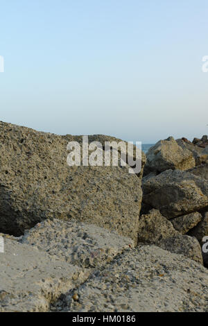 großen Steinen am Strand im Licht der untergehenden Sonne liegen Stockfoto