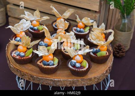 Dessert-Törtchen mit frischen Beeren, Heidelbeeren, Dessert Tartelettes mit Sahne und frischen Heidelbeeren, Johannisbeeren, Brombeeren, Physalis, Kiwi. Süße Beere Summe Stockfoto