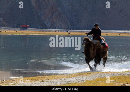 Kirgisen reiten auf einem Kamel am Karakul-See, Autonome Region Xinjiang, China. Stockfoto