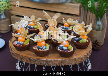 Dessert-Törtchen mit frischen Beeren mit Dekoration auf den Tisch. Kuchen für den Außenbereich feiern. Stockfoto