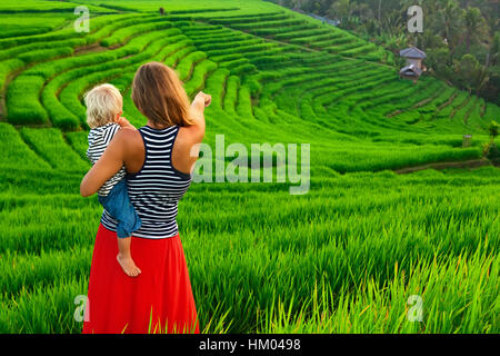 Schöne Aussicht auf balinesischen Felder. Naturspaziergang in grüne Reisterrassen. Glückliche Mutter halten glückliches kleines Baby.  Reisen mit Kind Stockfoto