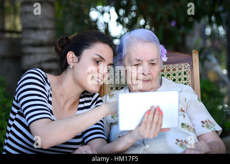 Mädchen zeigen, wie man Tablet zu Oma zu arbeiten Stockfoto