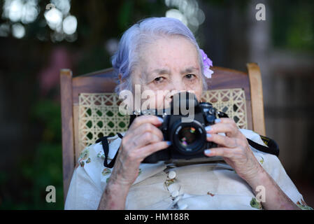Oma Spiel mit DSLR-Kamera sitzen im park Stockfoto