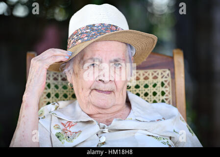 alte Oma Porträt im Hut im Freien sitzen Stockfoto