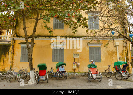 Cyclo-Fahrer und gelbe Wände in der malerischen alten Stadt von Hoi an, Vietnam Stockfoto