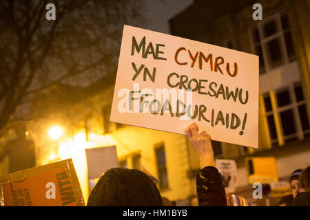 Ein Demonstrant hält ein Plakat Aufnahme Flüchtlinge nach Wales. Mehr als 1.000 Menschen versammelten sich in Cardiff gegen Präsident Trump Verbot von Menschen aus bestimmten muslimischen Ländern reisen in die USA. Menschen skandierten Unterstützung für Flüchtlinge und gegen den Faschismus. Stockfoto