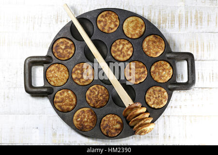 hausgemachte holländische Poffertjes in einer traditionellen gusseisernen Pfanne auf hölzernen Hintergrund Stockfoto