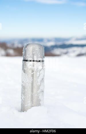 Metall Thermoskanne im Schnee auf einem verschneiten Berg Stockfoto