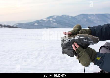 Mann, die Beseitigung von Schnee aus seinem Winterstiefel auf einem Berg Stockfoto