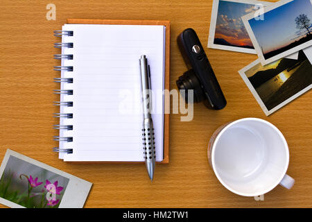 Notizbuch, Foto, Stift und Kamera. Auf dem Boden der Holztisch. Stockfoto