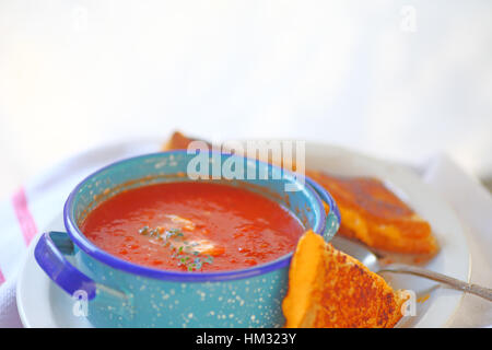 Tomatensuppe in einer blauen Schüssel mit einem Käse-Sandwich geschnitten in Dreiecke und Platz für text Stockfoto