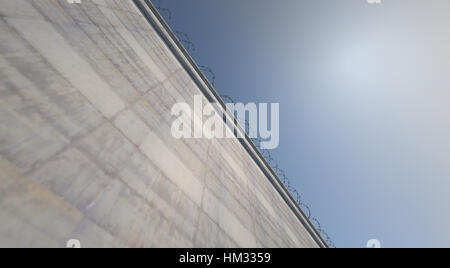 Ein 3D Rendering einer massiv Beton Hochsicherheits-Wand garniert mit Stacheldraht auf blauen Himmelshintergrund Stockfoto