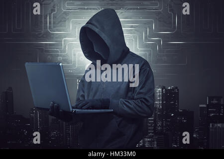Mit Kapuze Hacker halten Laptop während des Tippens vor digitalen Stadt Hintergrund Stockfoto