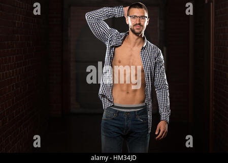 Portrait eines jungen körperlich Fit Mann In Jeans und T-shirt, zeigt seine gut ausgebildeten Körper - muskulöse athletische Bodybuilder Fitness Model posiert nach E Stockfoto