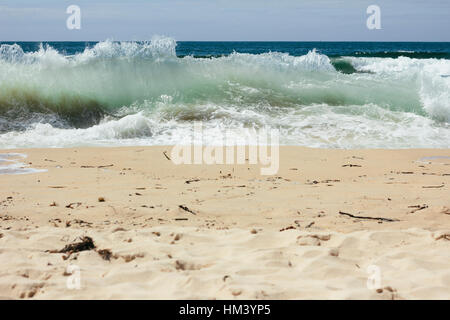 Wellen auf den Schmutz bedeckt Strand mit der blauen Horizont im Hintergrund Stockfoto