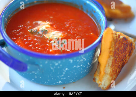 Tomatensuppe mit frischem Thymian in einen Topf Schüssel mit einem Käse-Sandwich in Dreiecke schneiden Stockfoto