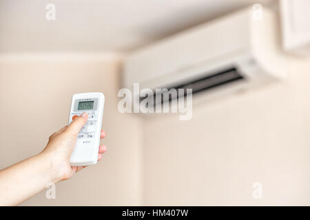 Nahaufnahme einer Hand mit einer Fernbedienung für die Klimaanlage einschalten. Stockfoto