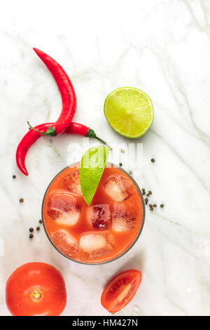 Bloody Mary Cocktail, geschossen von oben auf eine weiße Marmor Textur mit rote scharfe Chilischoten, Scheiben Limetten, Tomaten und Exemplar Stockfoto