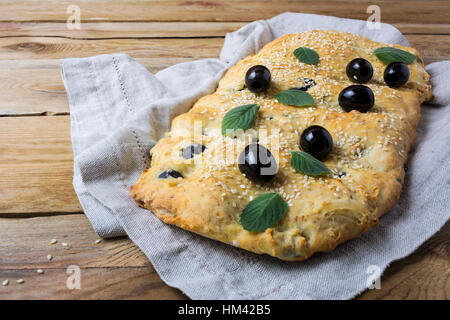 Italienisches Brot Focaccia mit Oliven. Hausgemachte traditionelle Brot auf dem rustikalen Tisch. Stockfoto