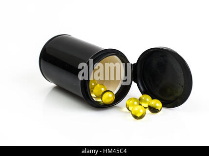Kleine runde gelbe Gelatinekapseln in schwarzem Glas Stockfoto
